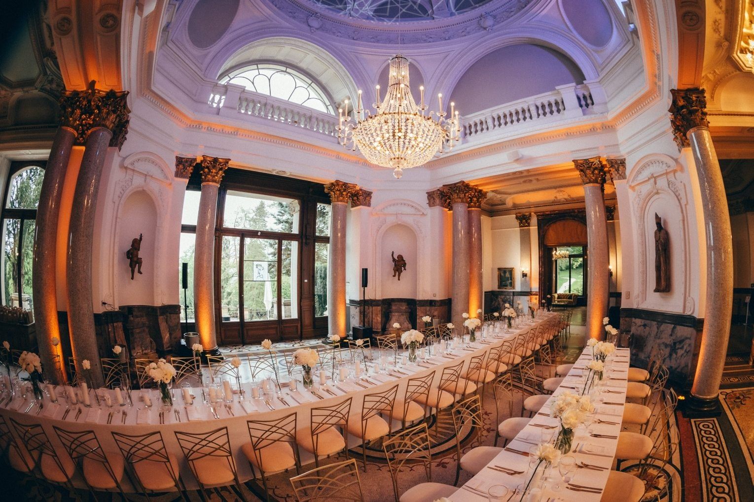 Der Kuppelsaal der Stella Rheni mit Marmorsäulen, Kronleuchter und langer festlich gedeckter Tafel am Abend