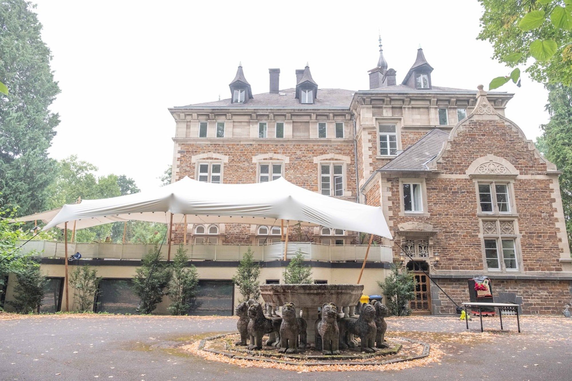 Schloss Vettelhoven in der Grafschaft mit gespanntem Sonnensegel auf der Terrasse über dem Vorplatz mit Brunnen