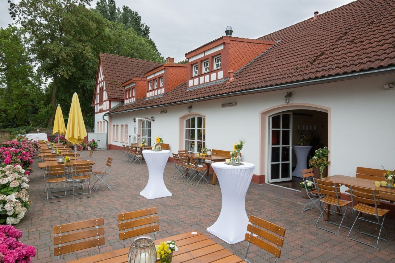 Terrasse vor dem Fachwerkhaus des Weilerhofs mit weißen Stehtischen, Sonnenschirmen und Hortensien