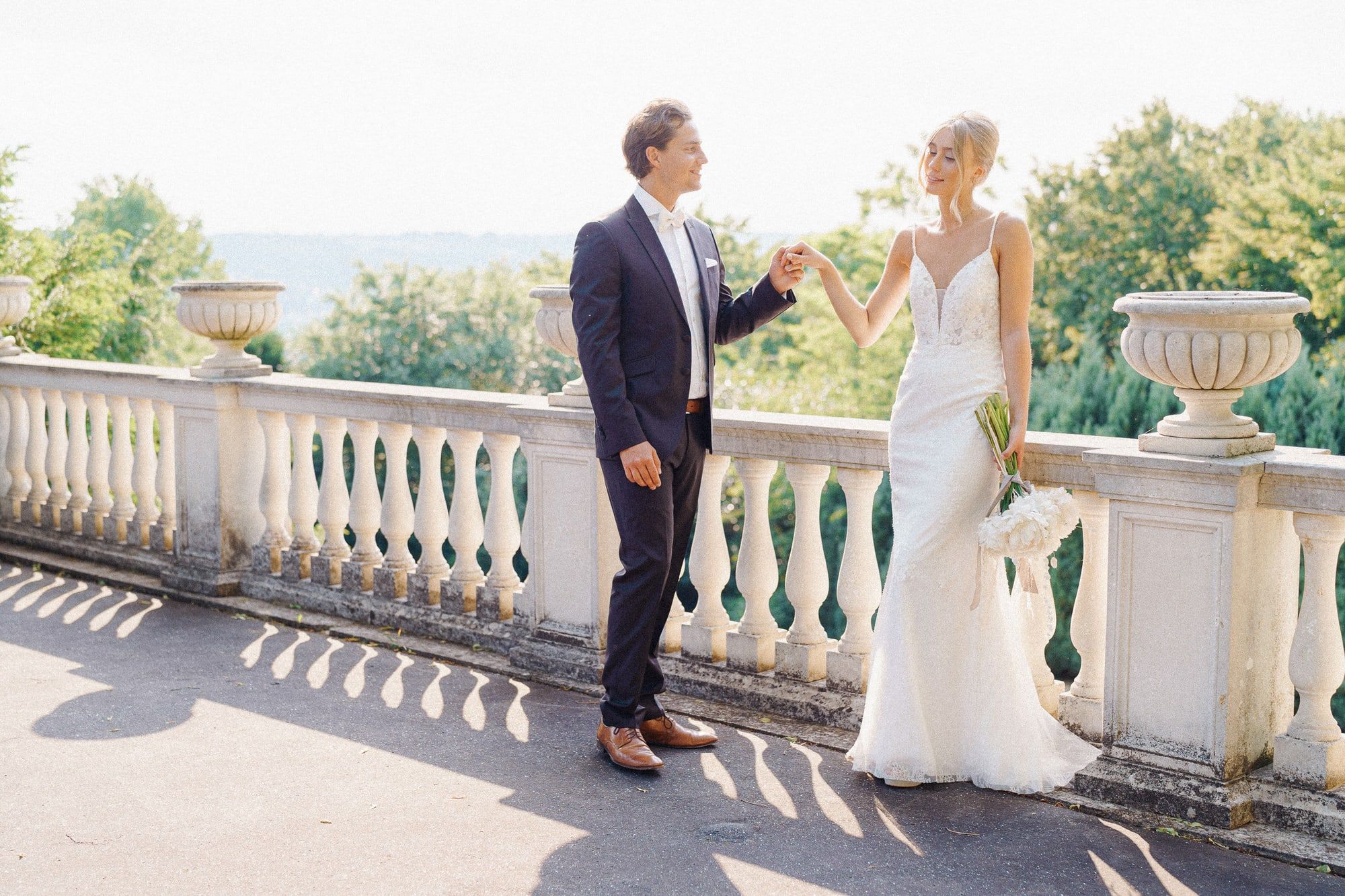 Brautpaar an der weißen Balustrade der Terrasse der Villa Heckenfels, dahinter Baumkronen und das Rheintal