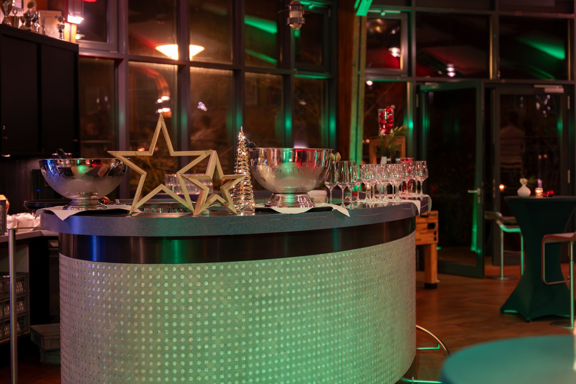 Geschwungene Bar der Rotunde mit leuchtender Front, Sektkühlern, Gläsern und Sternen als Dekoration