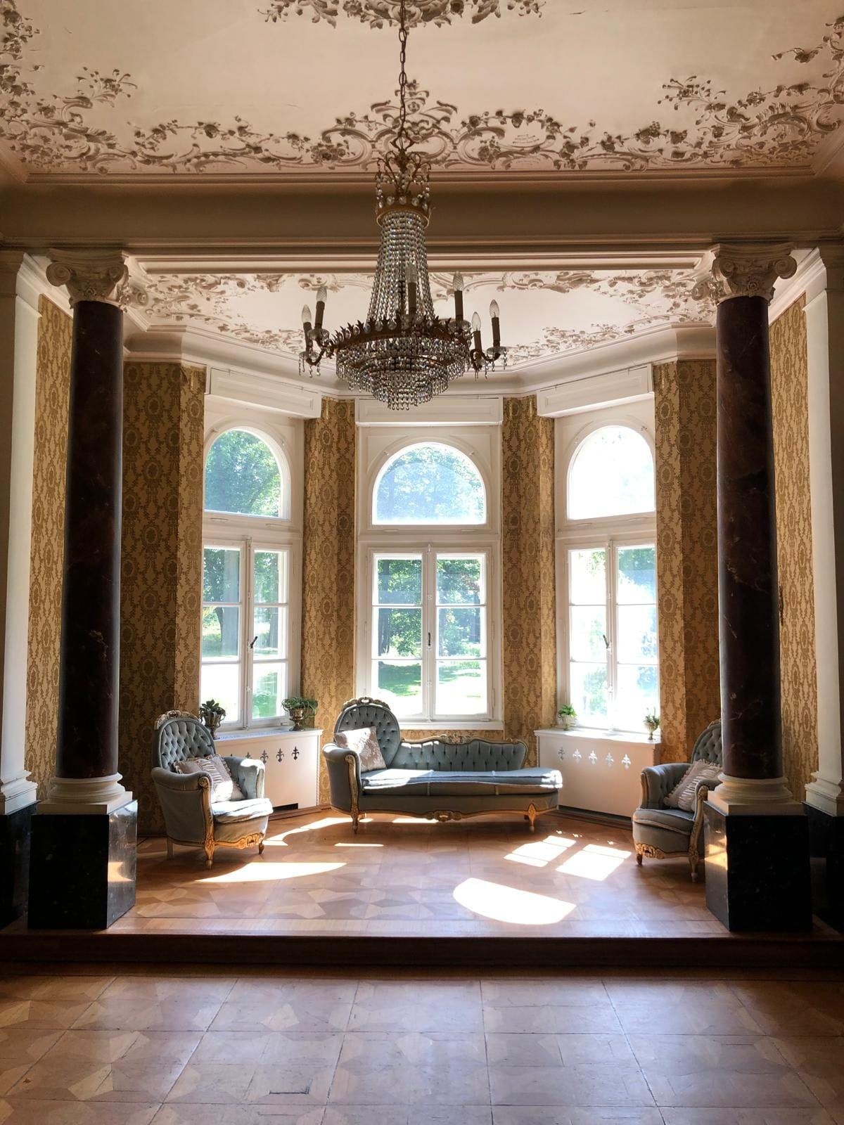 Erker-Salon mit Marmorsäulen, Stuckdecke, Kristalllüster und Rundbogenfenstern zum Park