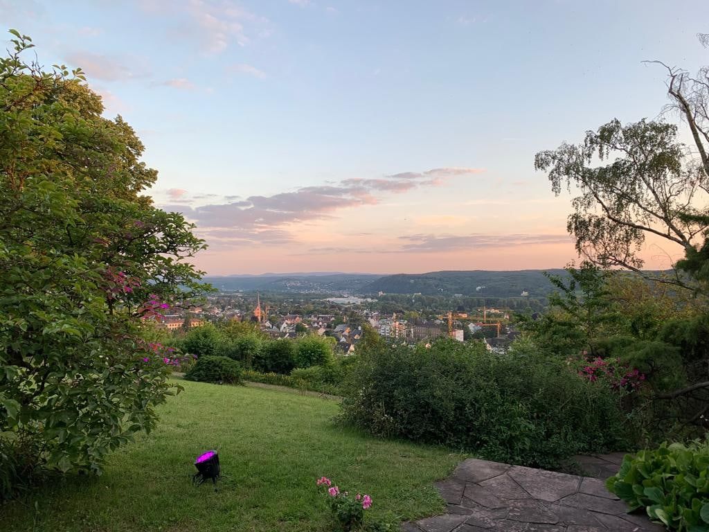 Abendstimmung im Garten der Villa Heckenfels, rosa Himmel über dem Rheintal und den Dächern von Bad Honnef