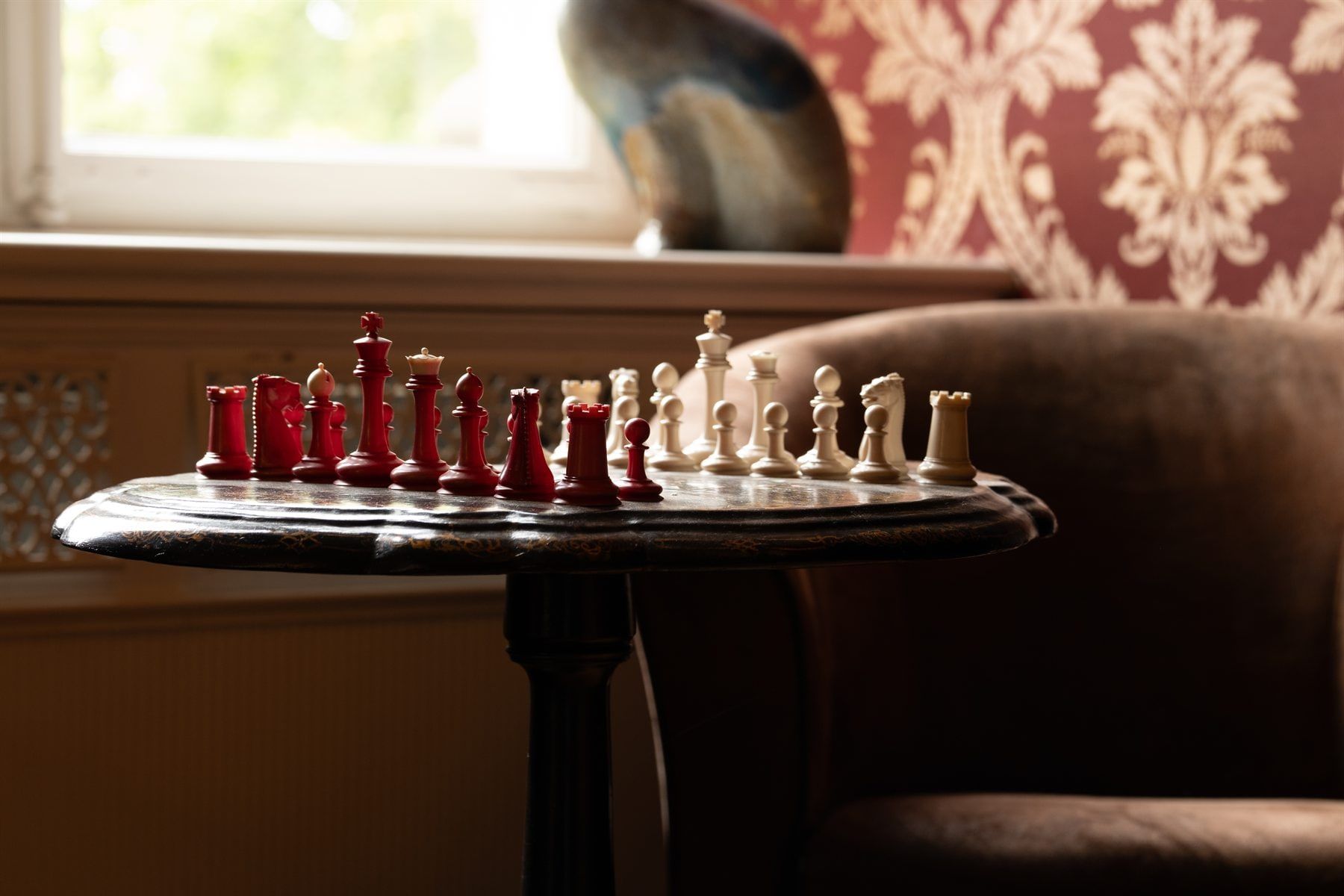 Antikes Schachspiel vor rot-goldener Damasttapete in einem Salon von Schloss Vettelhoven