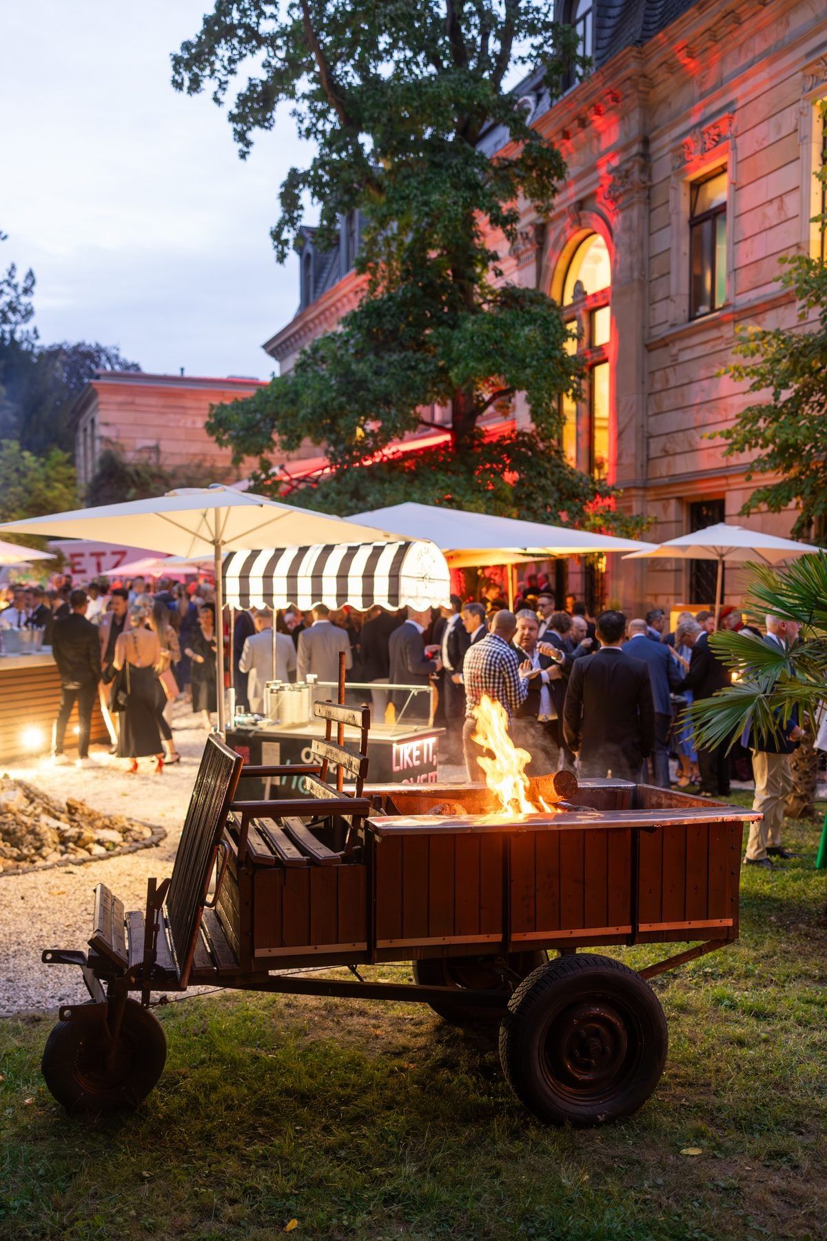 Abendlicher Firmenempfang auf der Terrasse der Villa mit Feuerschale, Showküche und Sonnenschirmen
