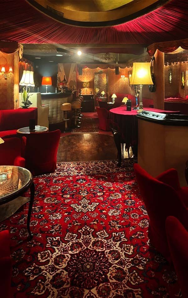 Blick über den gemusterten Orientteppich der Lounge auf Theke, Tischlampen und Samtsessel der Kokett Bar in Köln