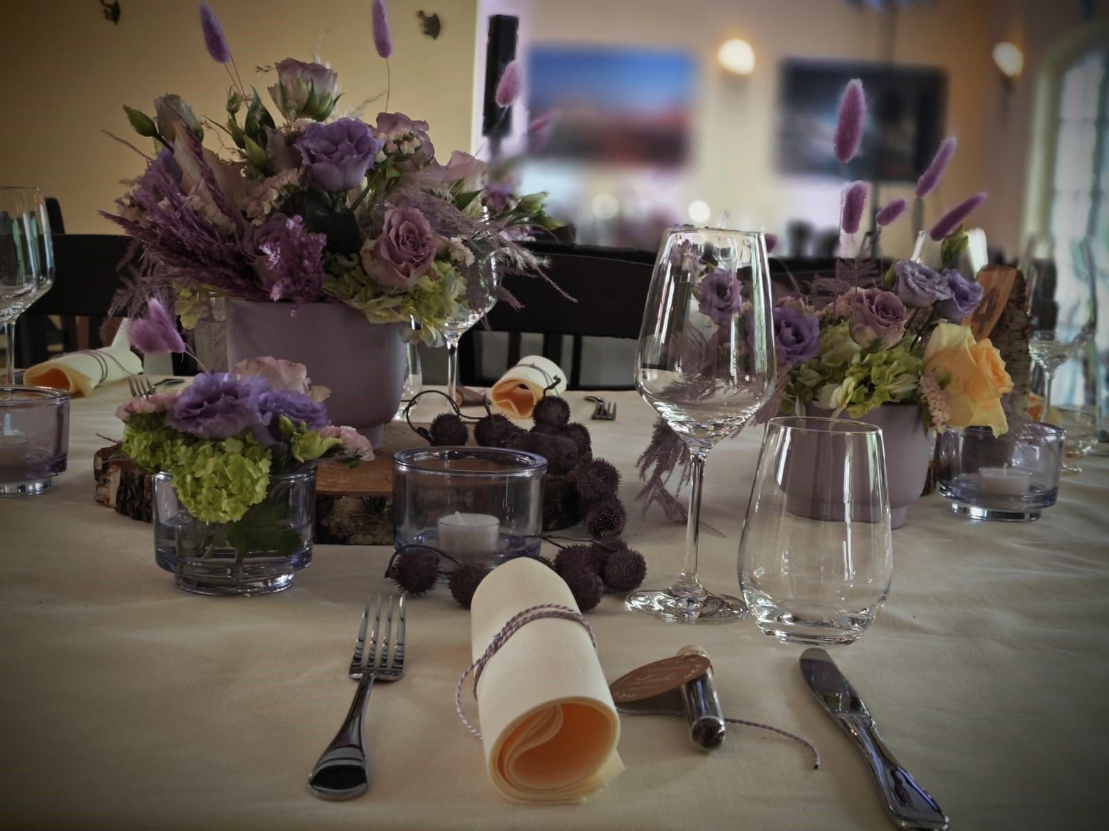 Tischdekoration mit lila Blüten, Lavendel und eingerollter Leinenserviette auf einer Hochzeitstafel