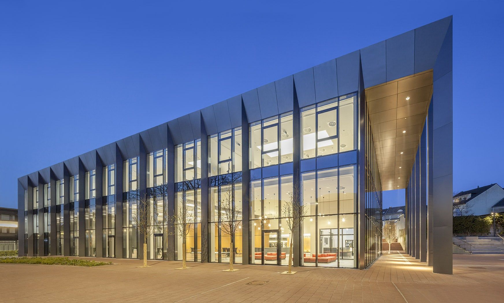 Das Rhein Sieg Forum in Siegburg zur blauen Stunde, eine lange Glasfassade mit schlanken Metallpfeilern und beleuchtetem Foyer