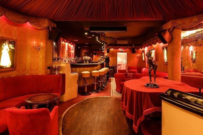 Lounge der Kokett Bar in Köln mit roten Samtsofas, Parkett-Tanzfläche, geschwungener Theke und rot verhängter Decke